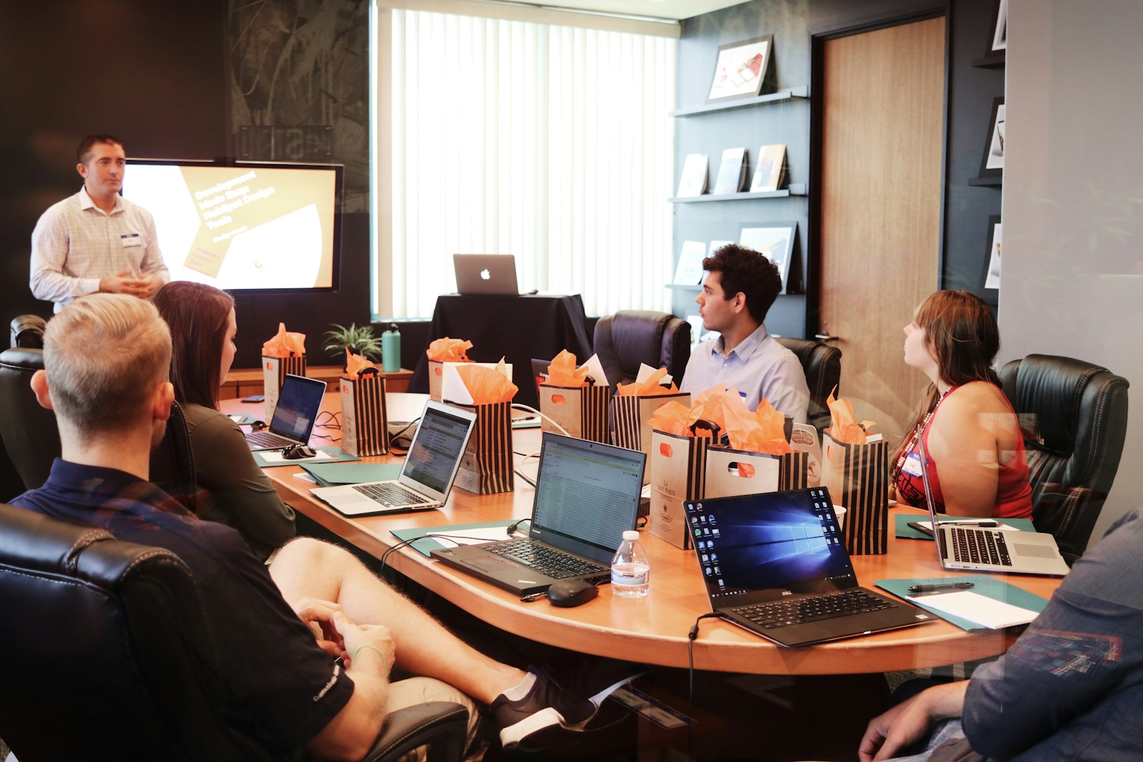 man standing in front of people sitting beside table with laptop computers, business